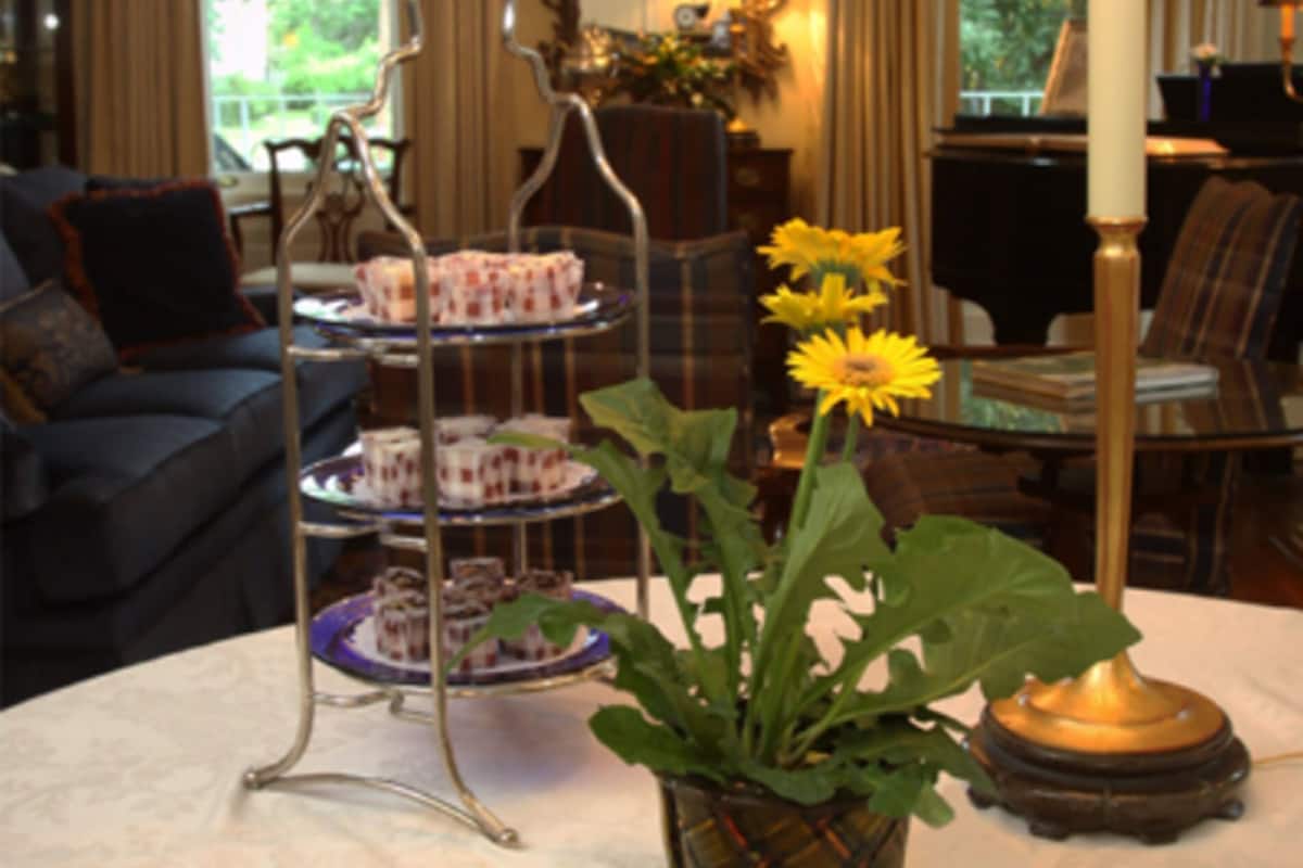 A dining table with a tray of cookies, a vase with flowers, and a candle holder.
