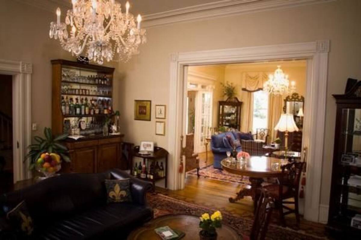 A traditional living room with a fireplace, a chandelier, and a dining area with a table and chairs.