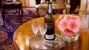 Una sala imponente con un piano de cola, una chimenea, un candelabro y una mesa con una botella y copas.