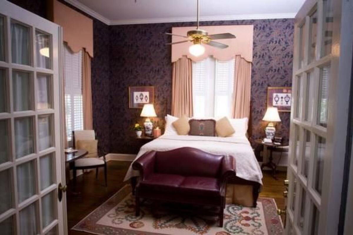 A bedroom with a bed, two bedside tables, a ceiling fan, and a window with curtains.