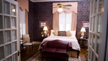 A bedroom with a bed, two bedside tables, a ceiling fan, and a window with curtains.