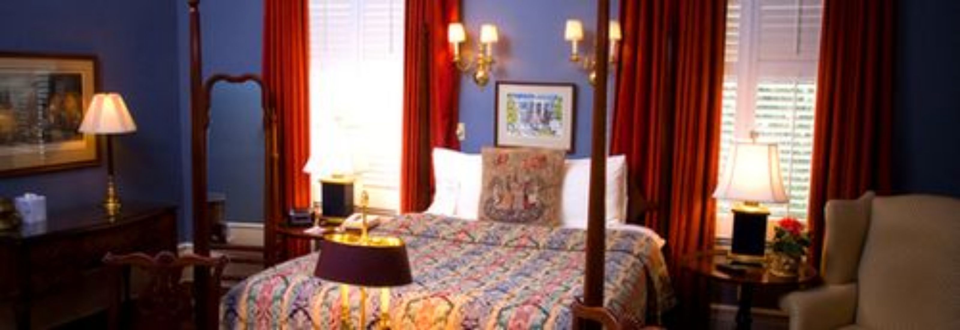 A hotel room with a bed, a nightstand, a lamp, a chair, and a window with curtains.