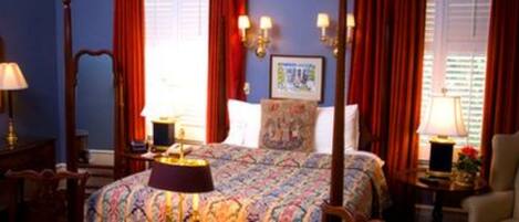 A hotel room with a bed, a nightstand, a lamp, a chair, and a window with curtains.