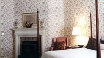 A bedroom with a four-poster bed, a fireplace, and a ceiling fan.