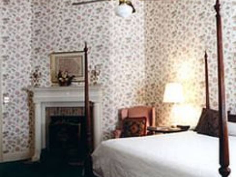 A bedroom with a four-poster bed, a fireplace, and a ceiling fan.