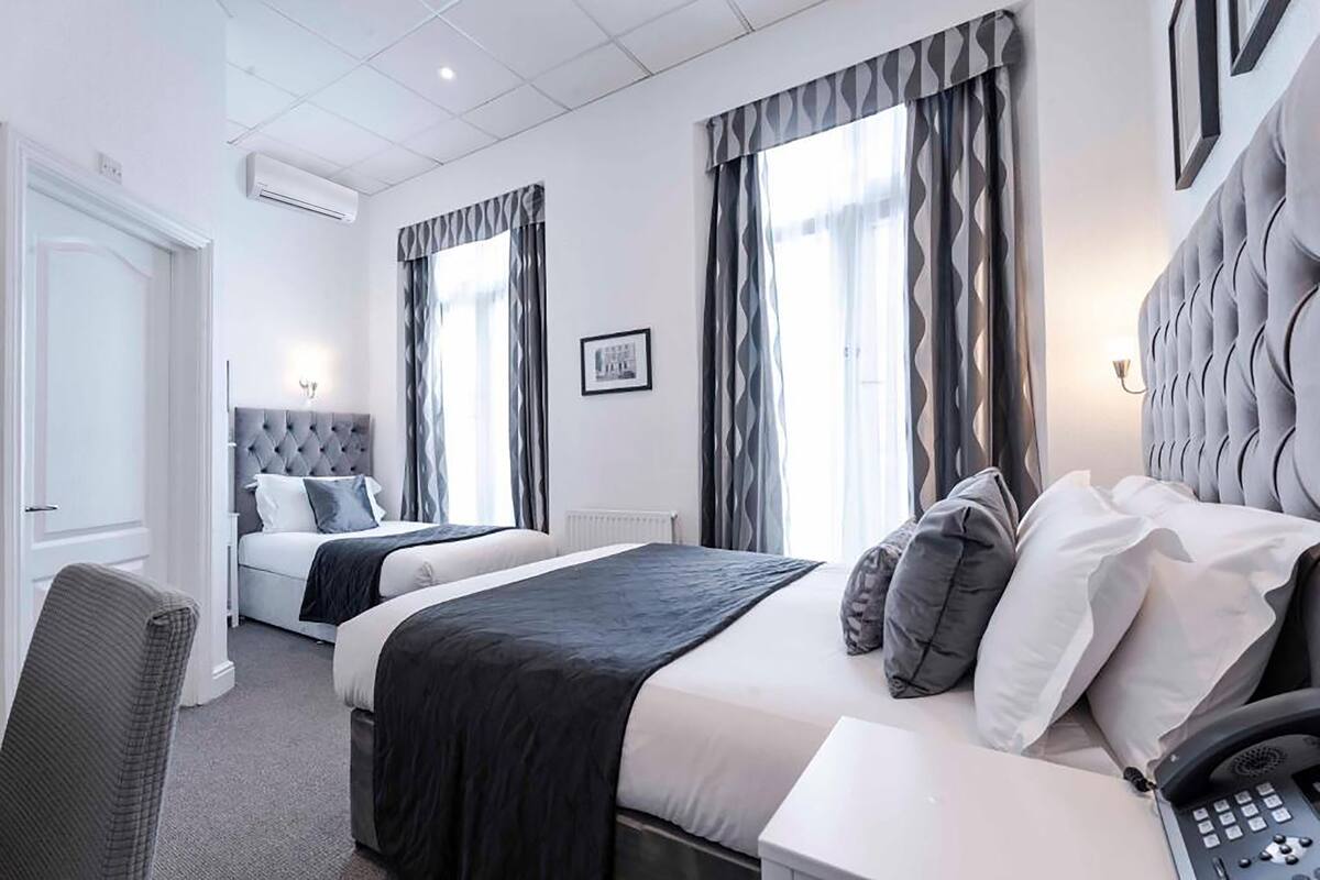A hotel room with two beds, a telephone, and a chair.