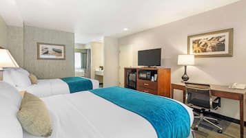 A hotel room with two beds, a desk, a TV, and a microwave.
