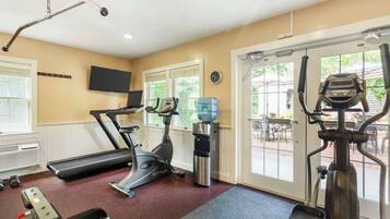 A gym with treadmills, an elliptical, a water dispenser, and a bench.
