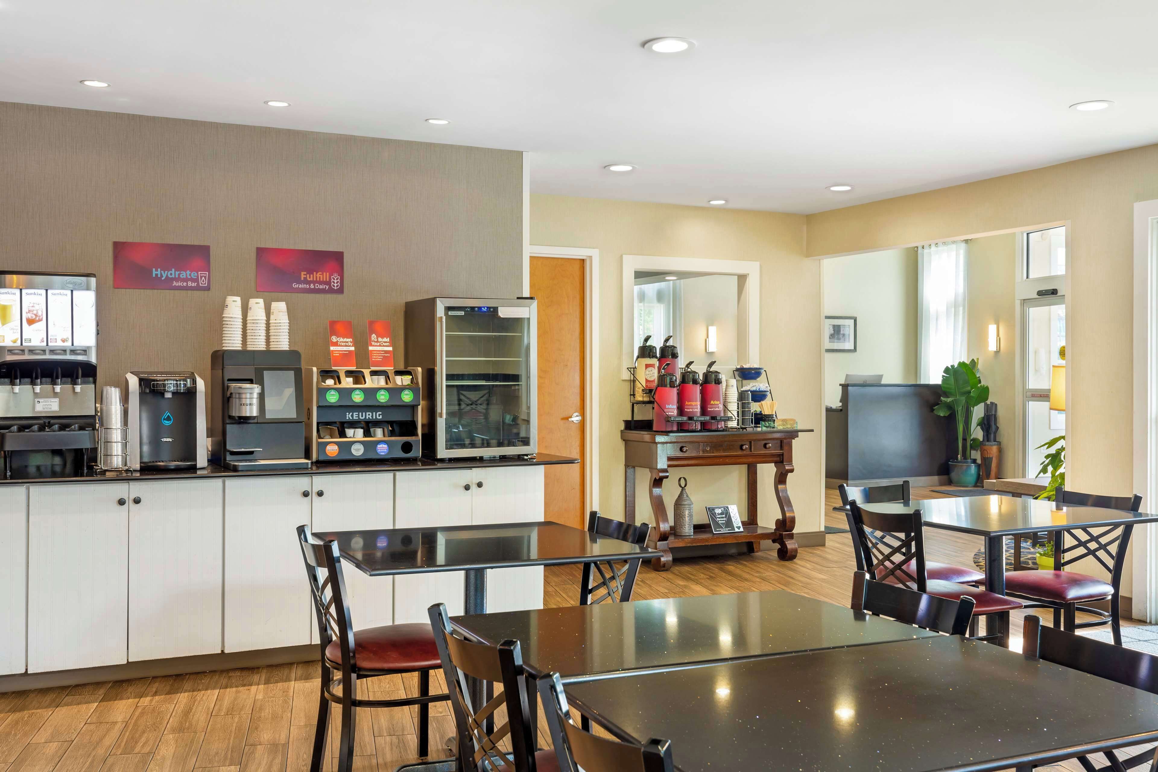 Una habitación de hotel con kitchenette, un comedor con mesa y sillas, una cafetera y un refrigerador.