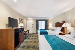 A hotel room with two beds, a desk, a television, and a minibar.