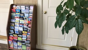 A wooden bookshelf filled with travel brochures and a potted plant beside a white door. - Kennebunk Gallery Motel & Cottages (Kennebunk)