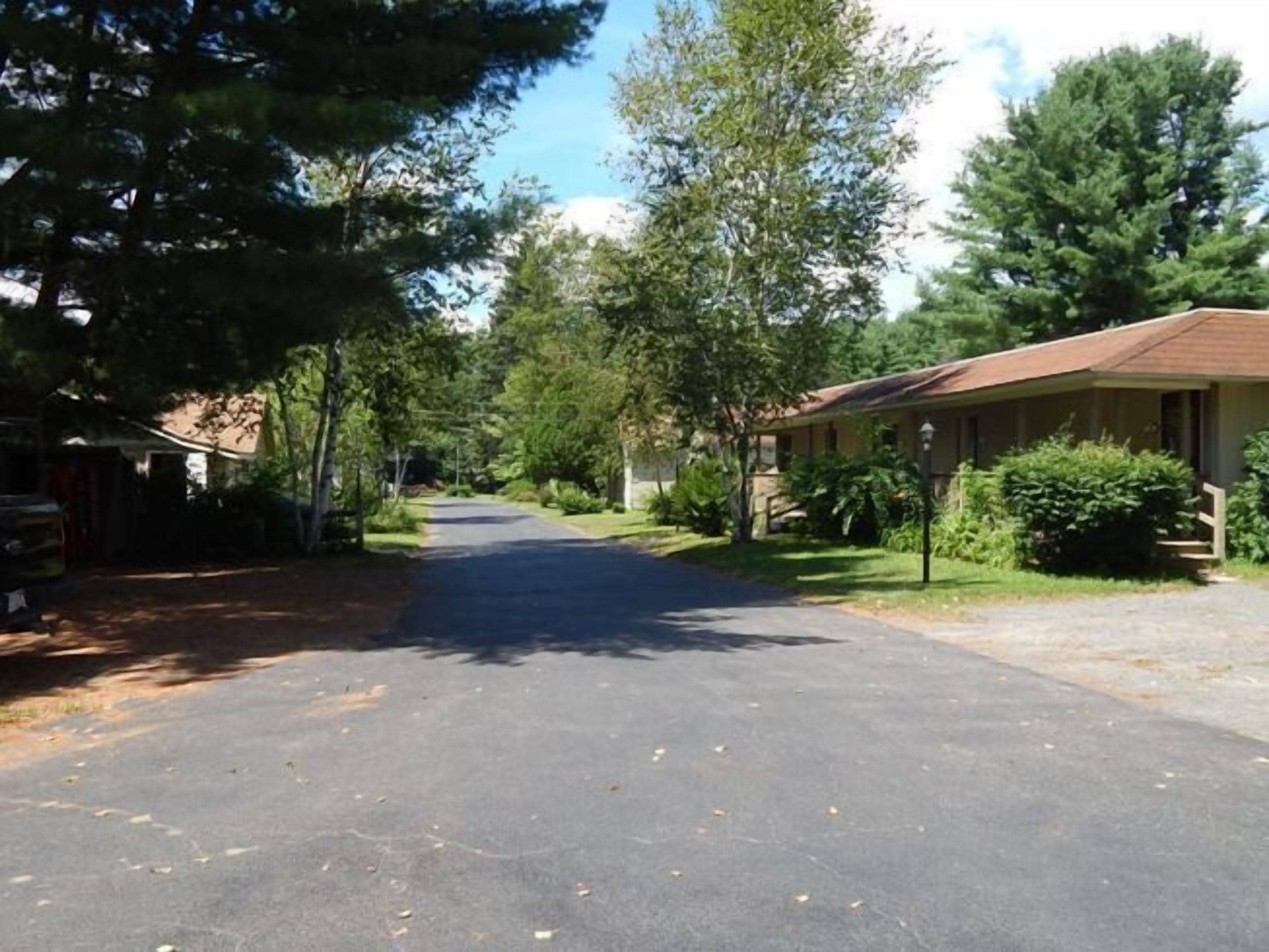 A residential street with houses on both sides, a clear sky, and a well-maintained road.