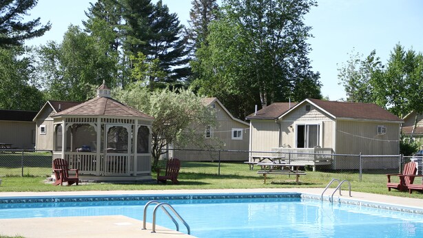 A swimming pool with a gazebo and two small sheds in a backyard. - Kennebunk Gallery Motel & Cottages (Kennebunk)