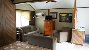 A compact bedroom with a bed, two sofas, a dresser, a television, and a painting on the wall. - Kennebunk Gallery Motel & Cottages (Kennebunk)