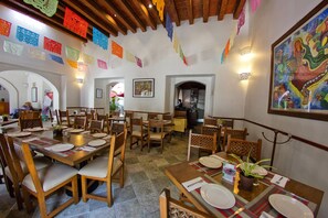 A dining area with wooden tables and chairs, decorated with colorful paper flags. - Hotel Casa Conzatti (Oaxaca)