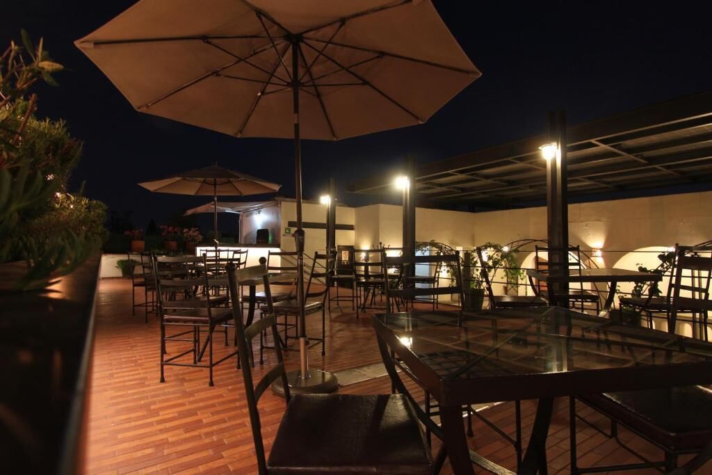 An outdoor dining area with tables and chairs, umbrellas, and potted plants.