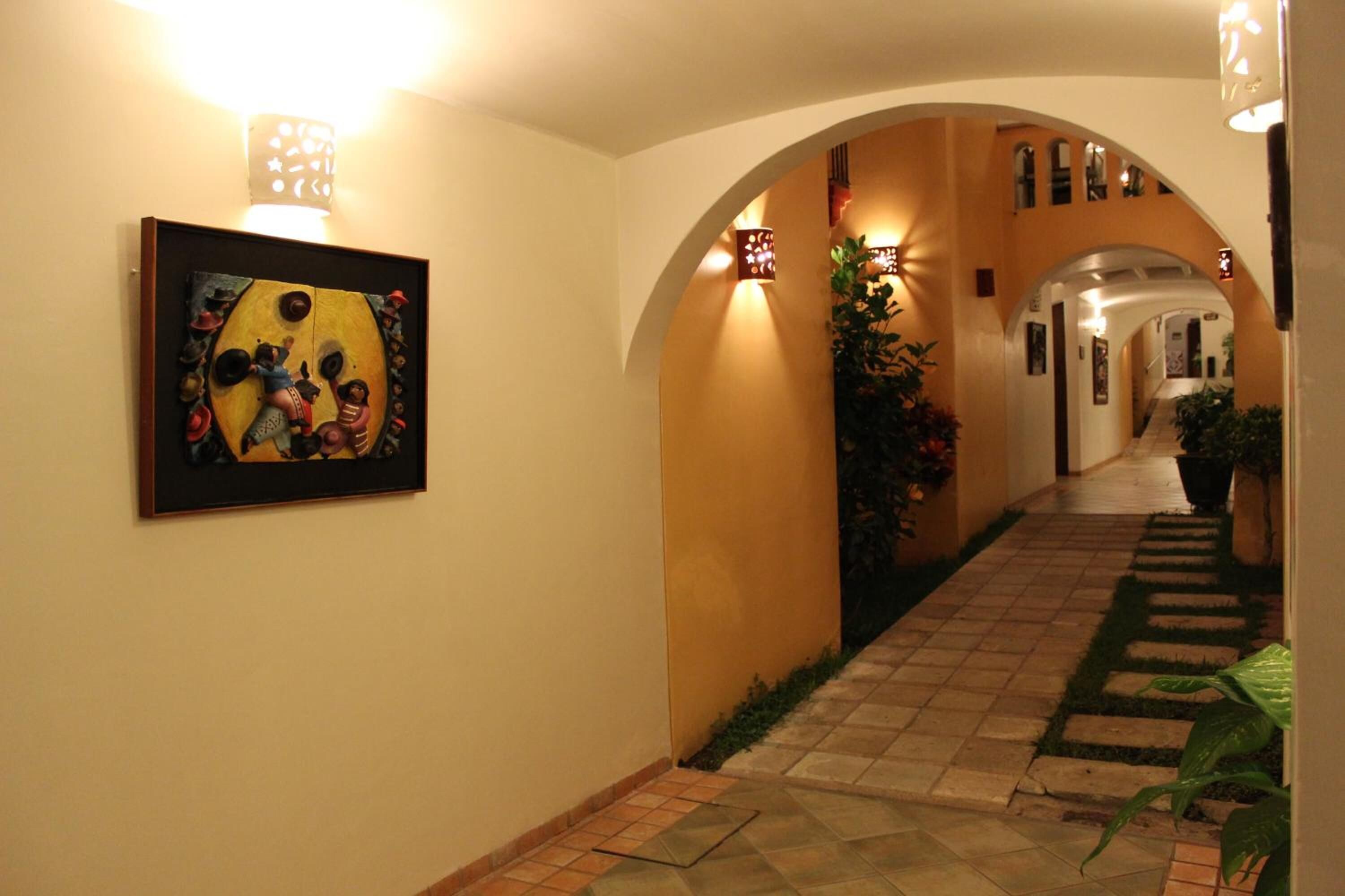Un pasillo con piso de baldosas, un arco y una obra enmarcada en la pared.