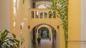 A corridor with arches, potted plants, and tiled flooring.