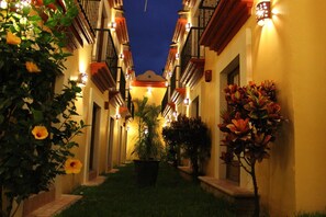 A narrow corridor with a central pathway flanked by buildings with balconies and warm lighting. - Hotel Casa Conzatti (Oaxaca)