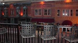 A restaurant with outdoor seating, featuring metal chairs and tables, and a brick building with windows in the background. - Mineral Palace Hotel & Casino (Deadwood)