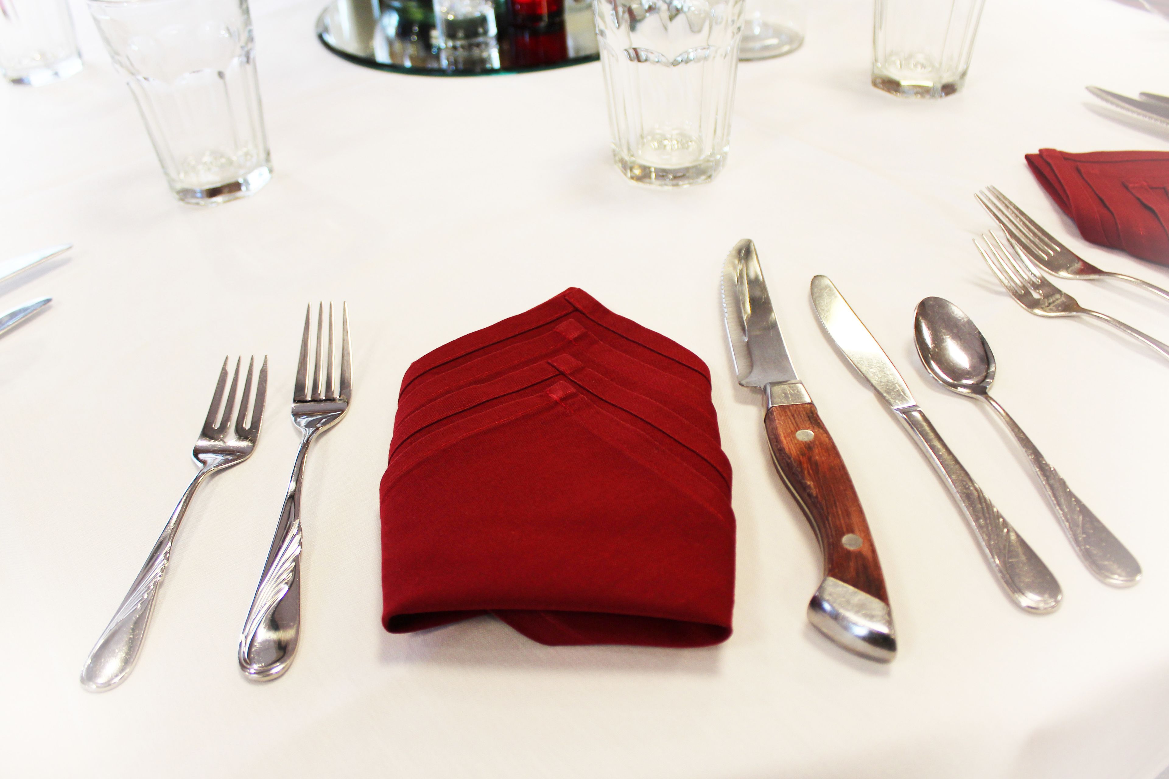 A table set with cutlery and a red napkin.