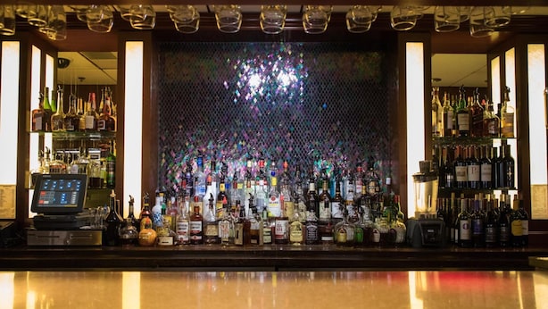 A bar area with a variety of liquor bottles, a cash register, and a decorative mirror wall. - Mineral Palace Hotel & Casino (Deadwood)