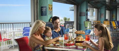 A family dining at an outdoor restaurant with a view of the ocean.