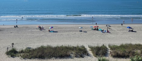 A beach with people, umbrellas, and a clear view of the ocean.
