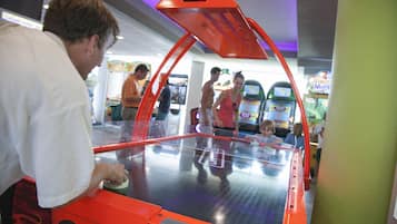 A gaming arcade with various machines and people playing.