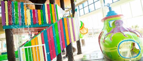A colorful play structure with a slide and a climbing wall.