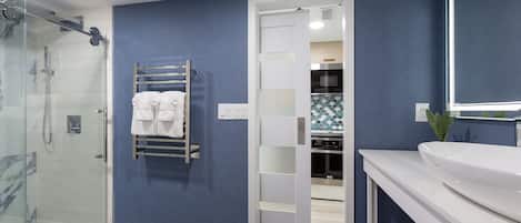 A modern bathroom with a glass shower enclosure, a white toilet, and a sink with a mirror.