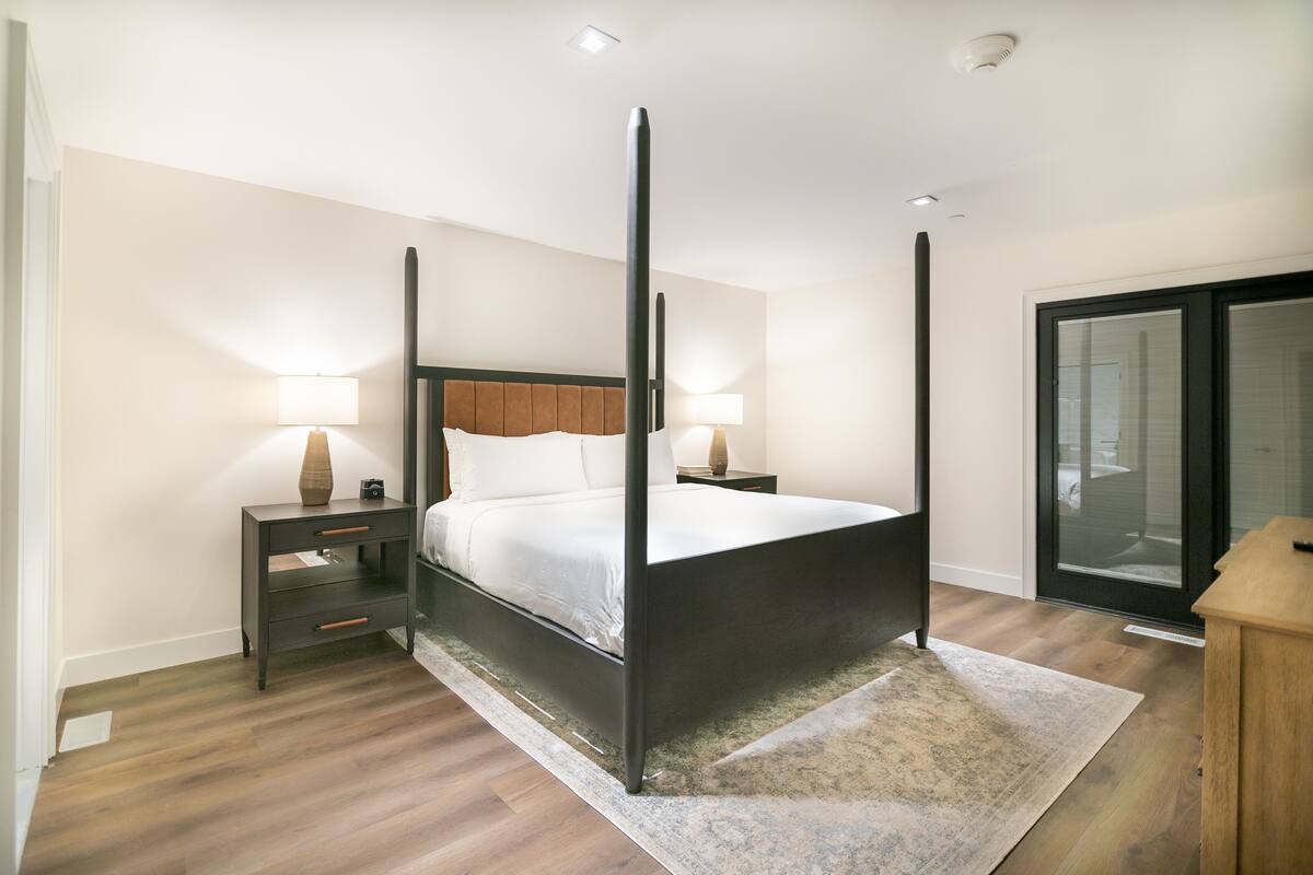 Ein modernes Schlafzimmer mit einem Himmelbett, Holzboden und einem großen Fenster.