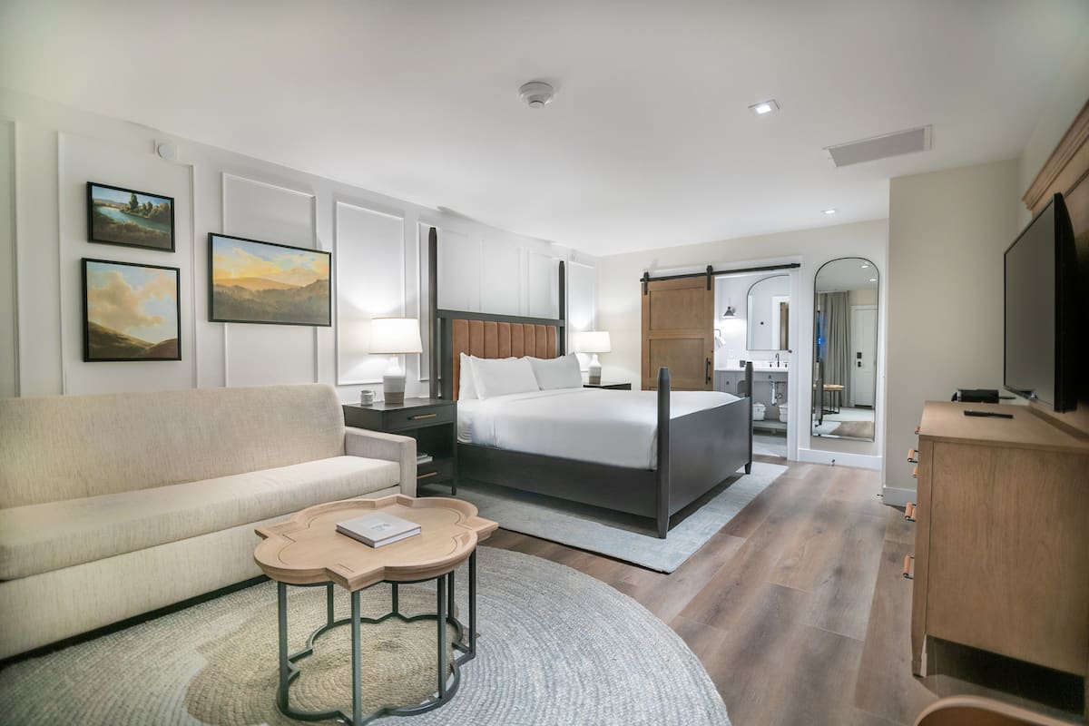 Ein modernes Hotelzimmer mit einem Bett, einer Couch, einem Nachttisch und einem Fernseher.