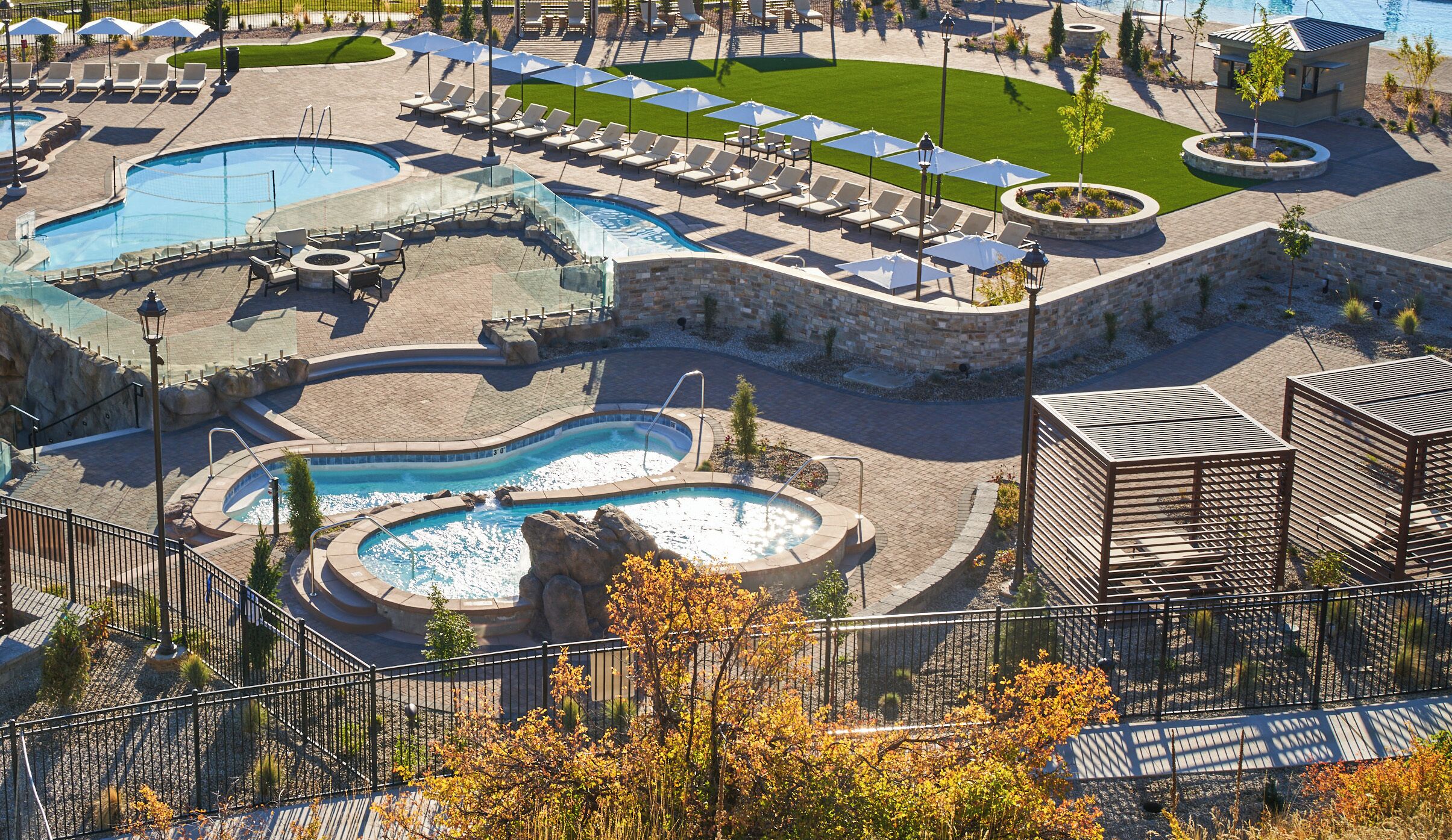 Ein Resort mit mehreren Schwimmbecken, Liegestühlen und einem Gebäude aus Stein.