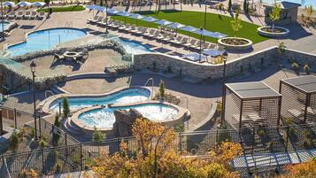 Ein Resort mit mehreren Schwimmbecken, Liegestühlen und einem Gebäude aus Stein.