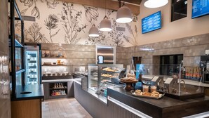 A modern kitchen area with a refrigerated display, a glass counter with pastries, and a menu board.