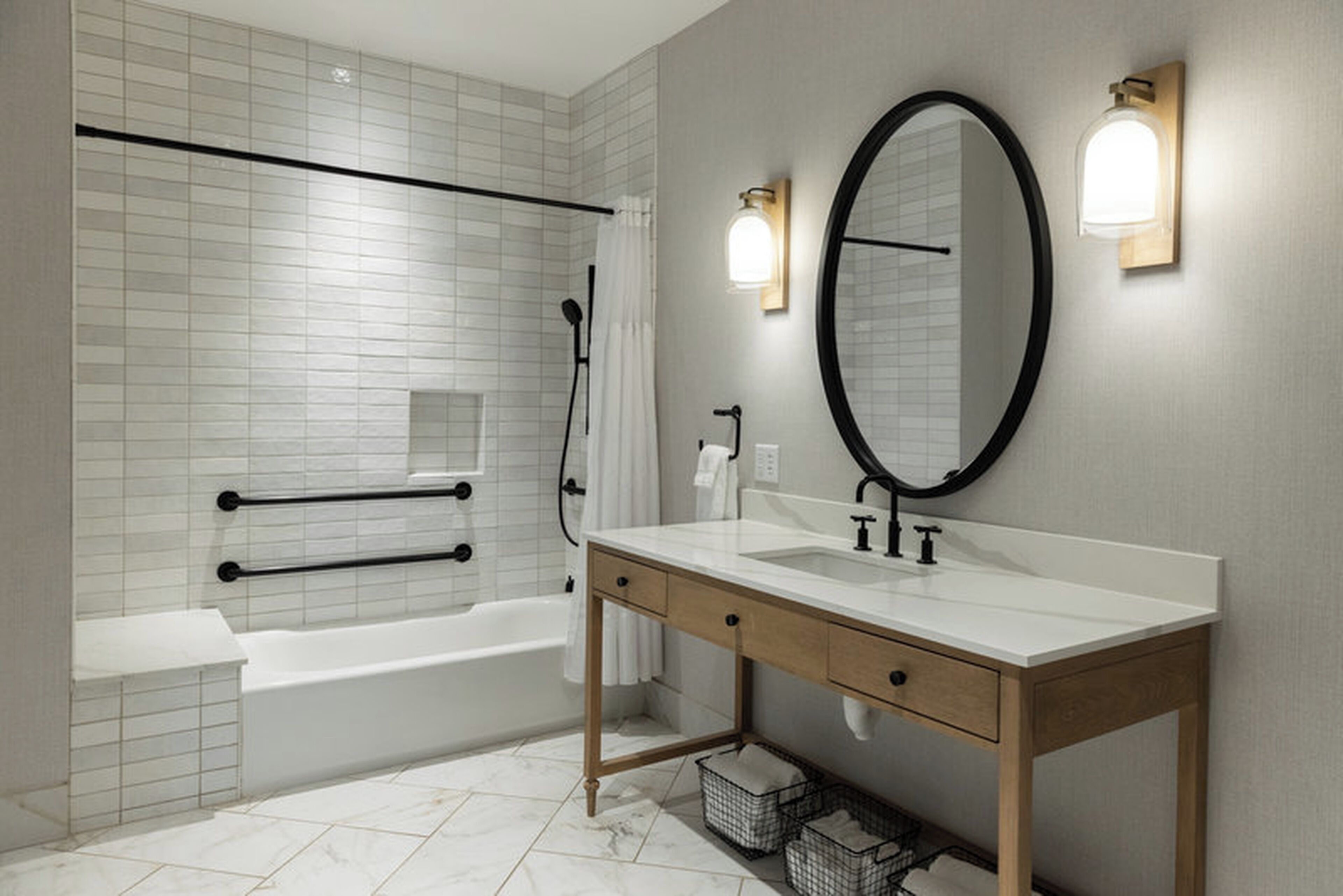 A modern bathroom with a white bathtub, a wooden vanity with a mirror, and a shower area.