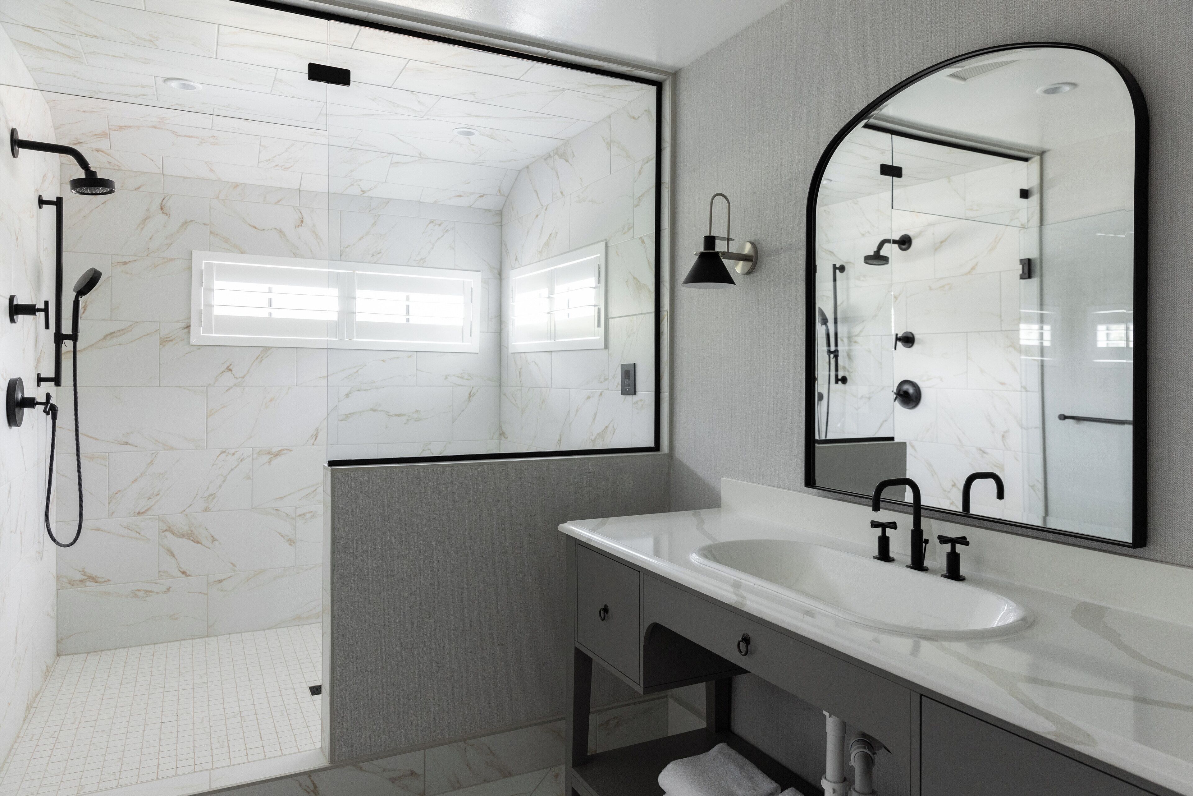 Un baño moderno con cabina de ducha, un espejo grande y un lavabo blanco.