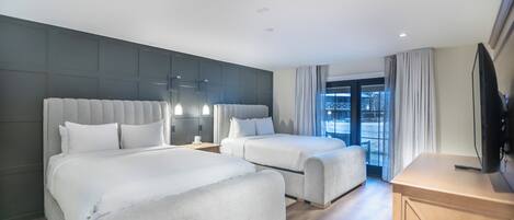A modern hotel room with two beds, a flat-screen TV, and a large window with curtains.