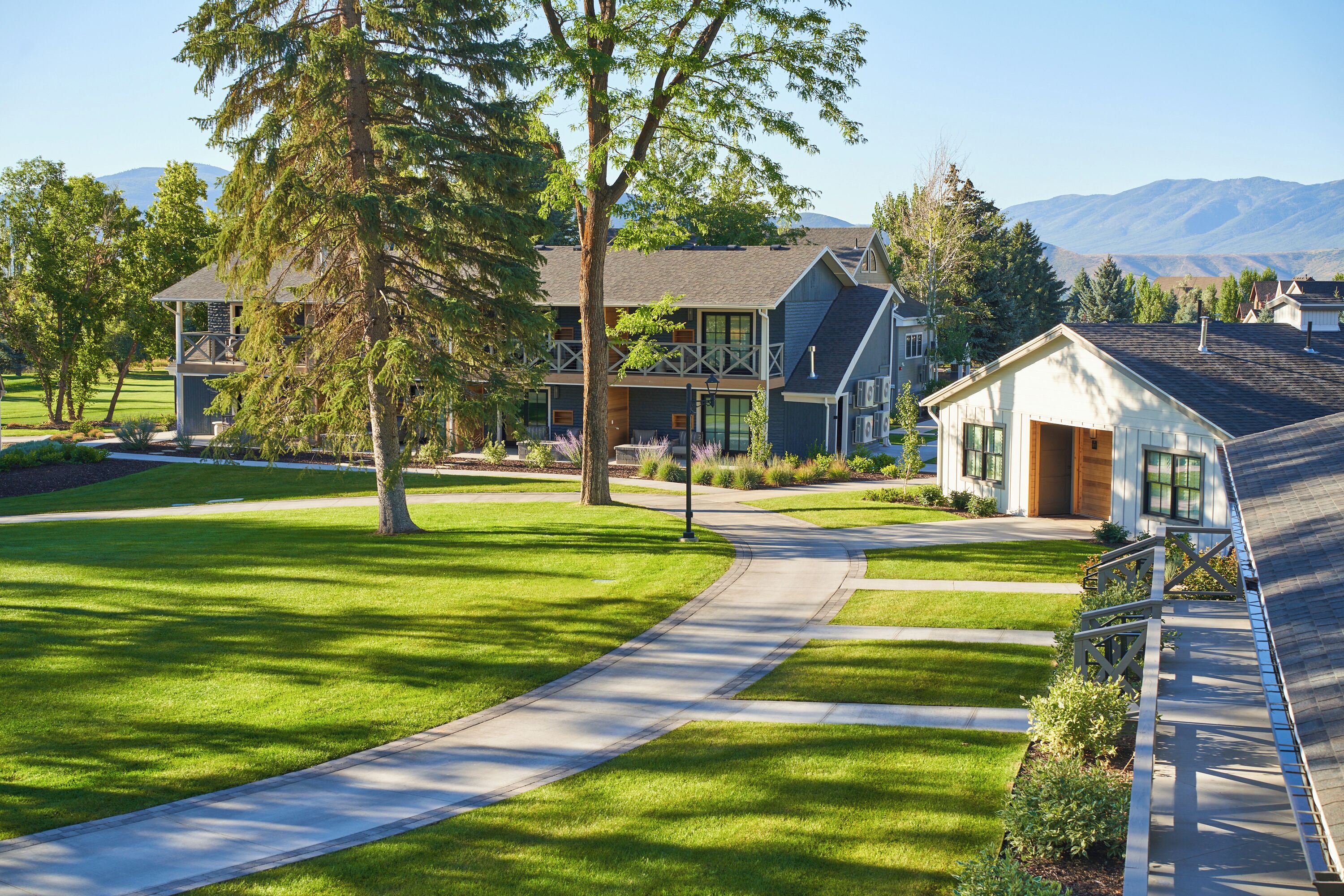 A residential area with modern houses, a well-maintained lawn, and a clear sky.
