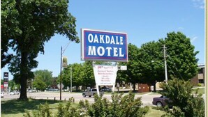 Et motel-skilt med navnet "Oakdale Motel" og et mindre skilt nedenunder, der reklamerer for "godkendte restauranter, køkkener og barer".