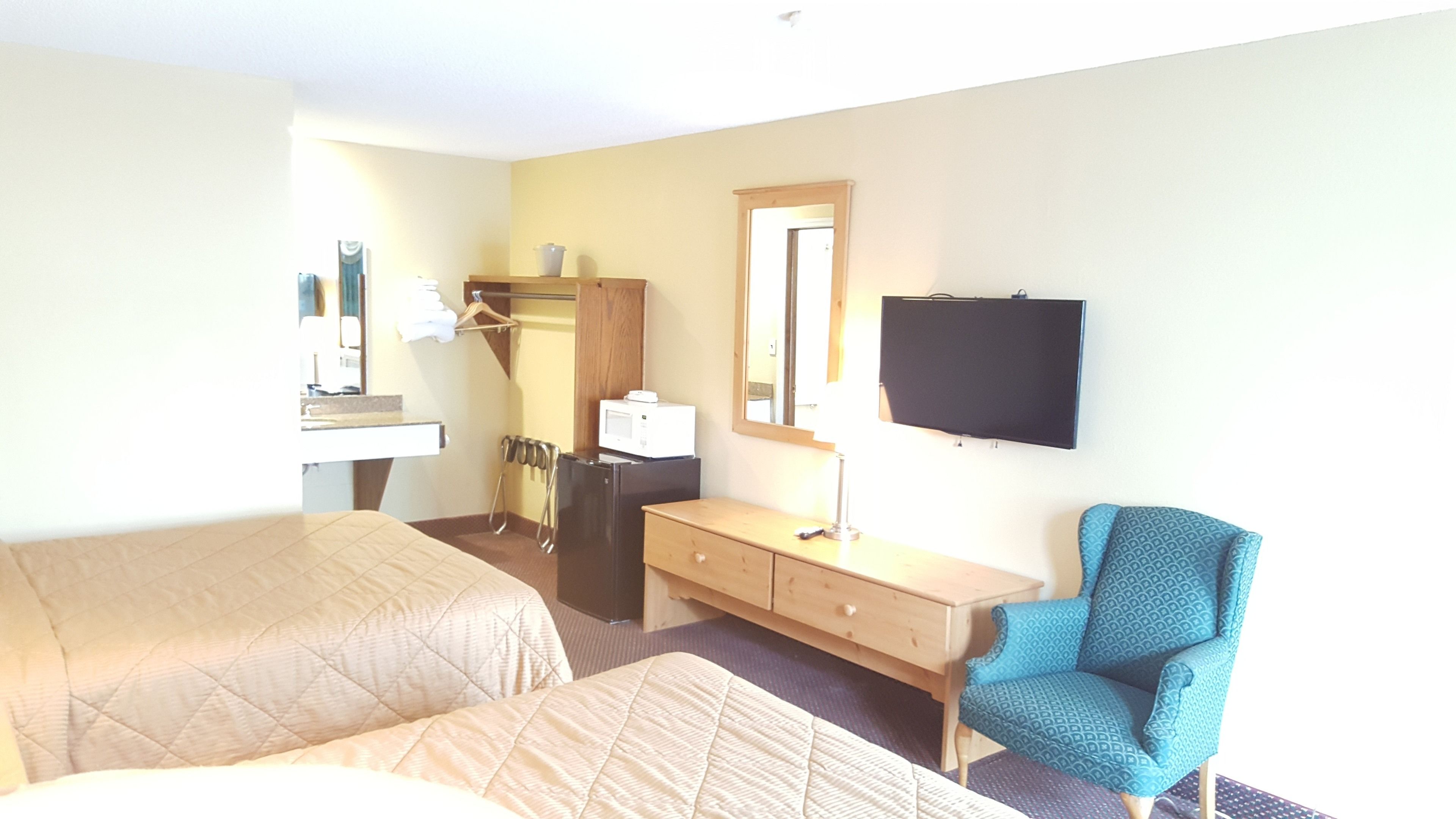 Une chambre d’hôtel avec deux lits, un bureau, une chaise, une télévision, un miroir et un four à micro-ondes.