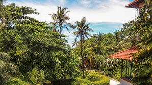 A lush garden with a water feature, a bridge, and a building with a red roof. - Bali Garden Beach Resort (Kuta)