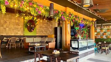 Un restaurante con una barra larga, asientos a rayas y una pared decorativa con plantas e iluminación.