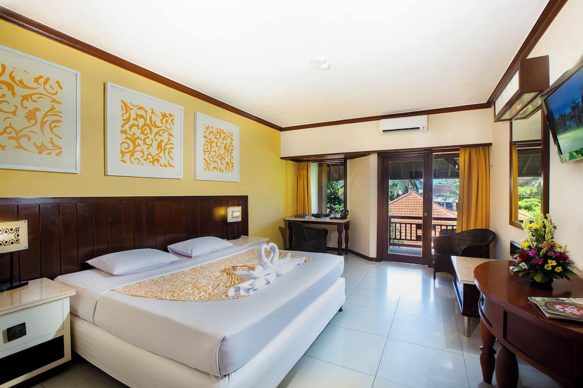 A hotel room with a large bed, a desk, a chair, and a balcony with a view.