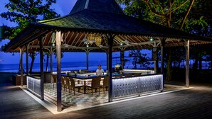 A gazebo with a checkered floor and a bar area, overlooking a beach and ocean. - Bali Garden Beach Resort (Kuta)
