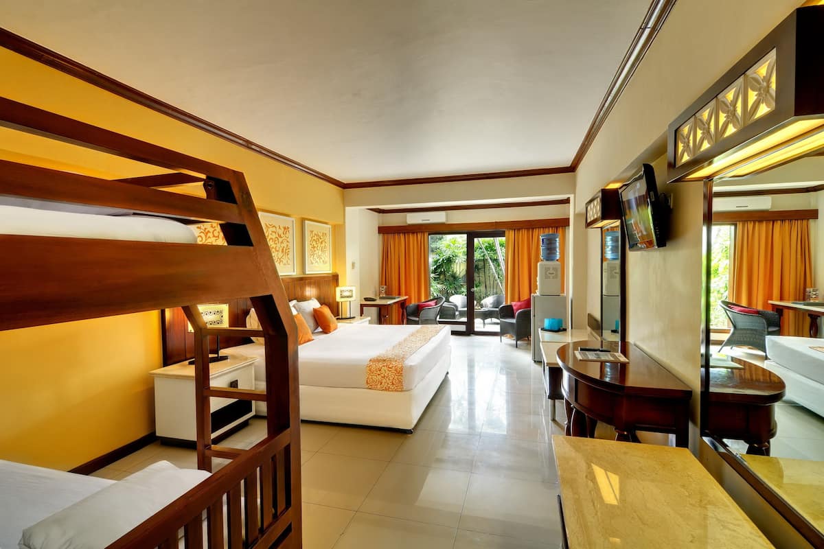 A hotel room with a bunk bed, a sofa bed, a desk with a chair, a TV, and a large mirror.