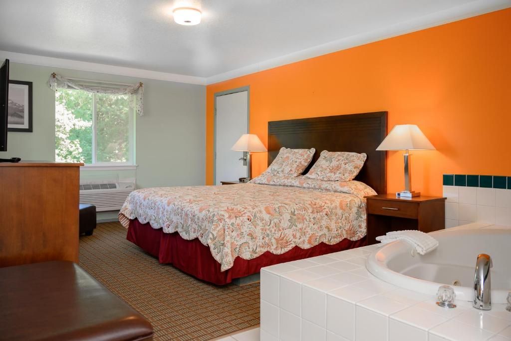 A hotel room with a bed, a bathroom with a bathtub, and a desk with a chair.