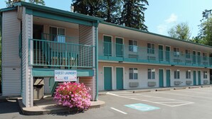 A motel with a guest laundry ice facility, a parking lot, and a row of rooms with balconies. - Sweet Home Inn (Sweet Home)