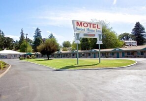 Ein Motel namens Sweet Home Inn mit einem Schild, einem Parkplatz und einer Reihe von Motelgebäuden.